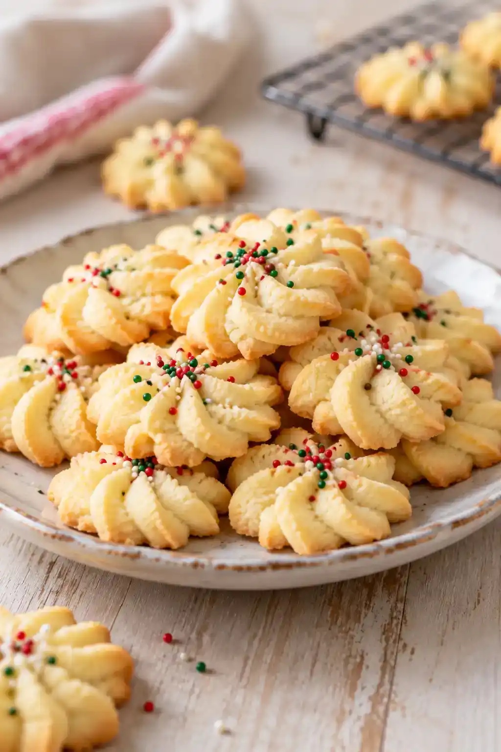 A batch of melt-in-your-mouth spritz cookies arranged on a ceramic plate.