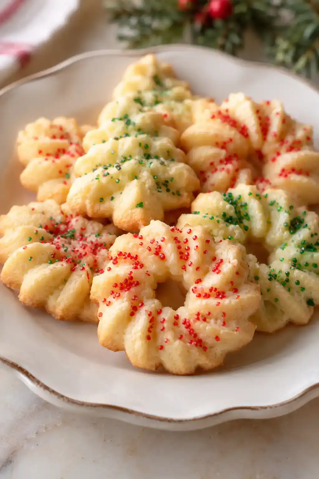 A batch of old-fashioned spritz cookies arranged on a ceramic plate.